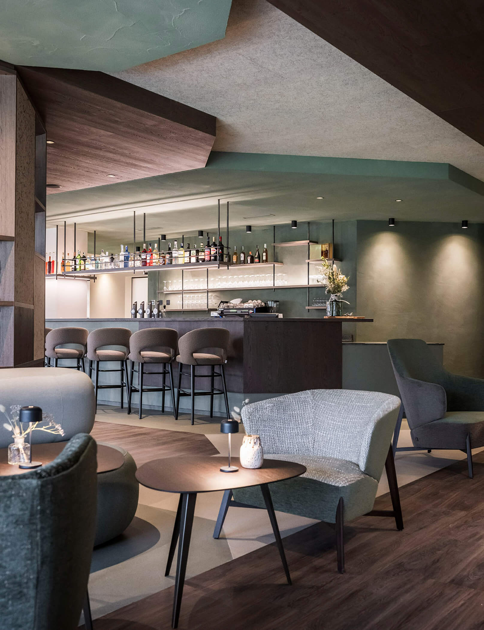 Bar mit Tischen und Stühlen, im Hintergrund die Theke mit Hockern und diversen Flaschen - Hotel Patris