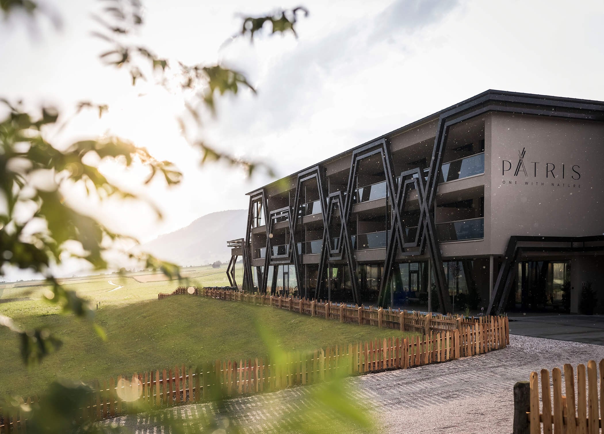 Das Hotel Patris von außen mit Holzzaun und grünen Wiesen