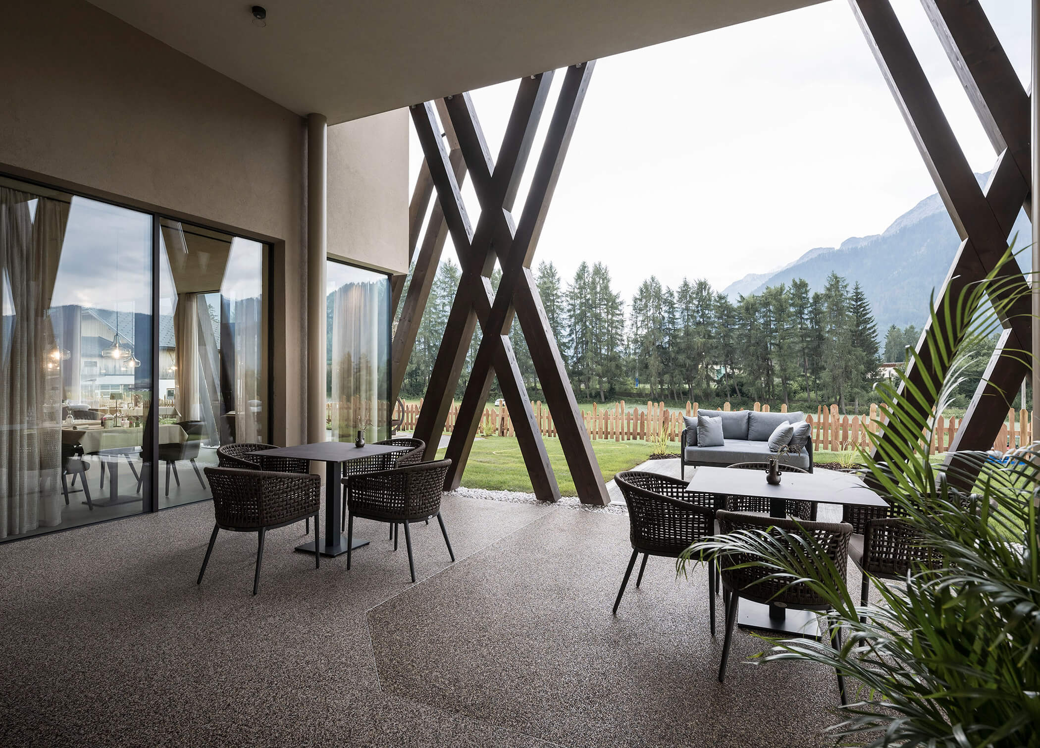 La terrazza dell'Hotel Patris con tavoli e sedie in primo piano e un divano sullo sfondo