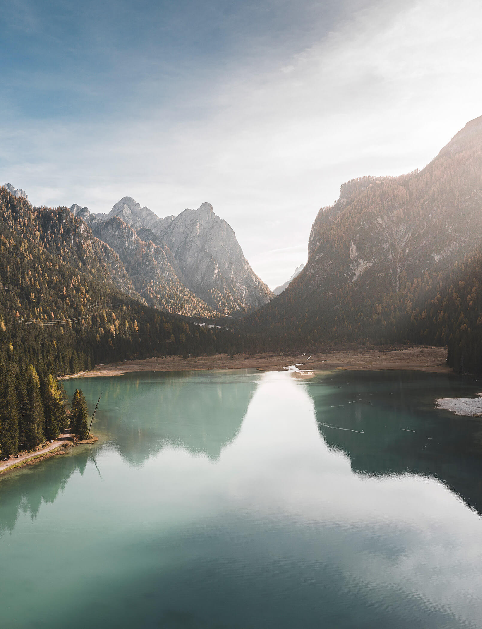 Il Lago di Dobbiaco circondato da alberi e montagne - Hotel Patris