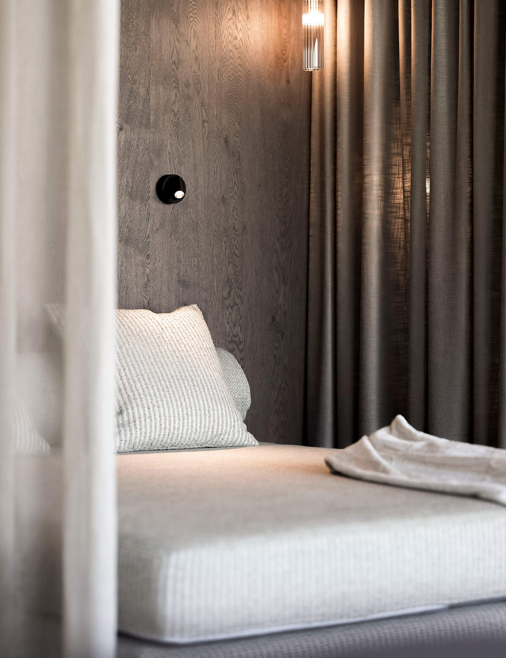 Accogliente angolo coccole con cuscini bianchi e grigi e parete in legno scuro - Hotel Patris