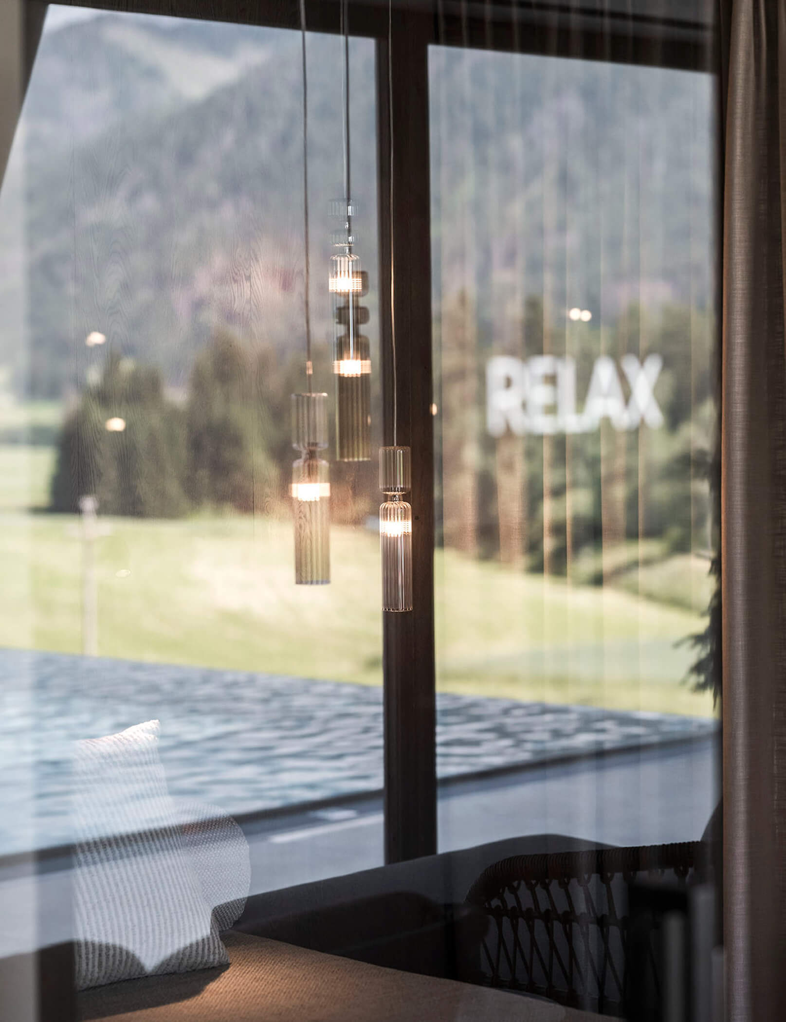 Lettino nella sala relax, la piscina esterna si riflette nella finestra - Hotel Patris