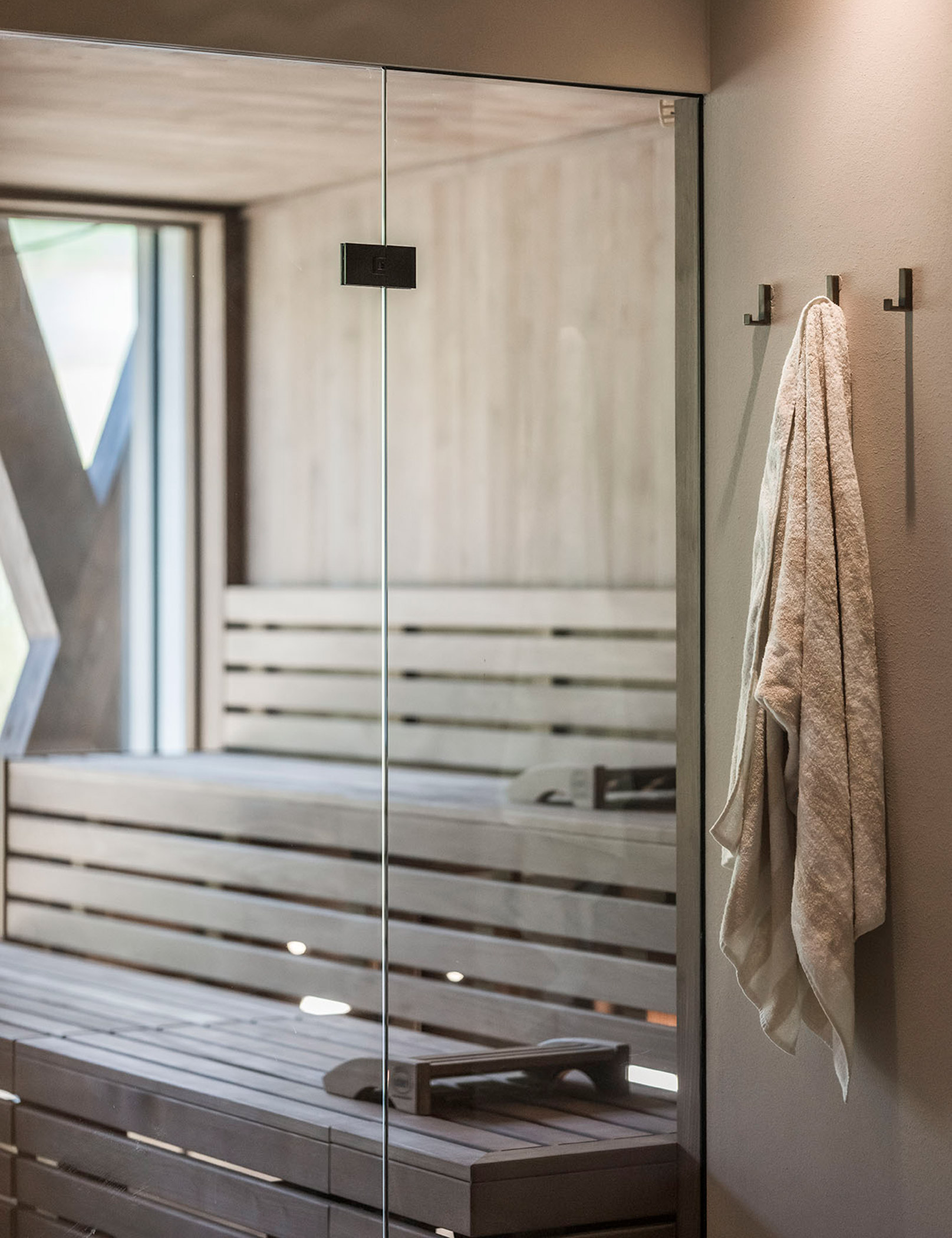 Weißes Handtuch am Haken, im Hintergrund die finnische Sauna