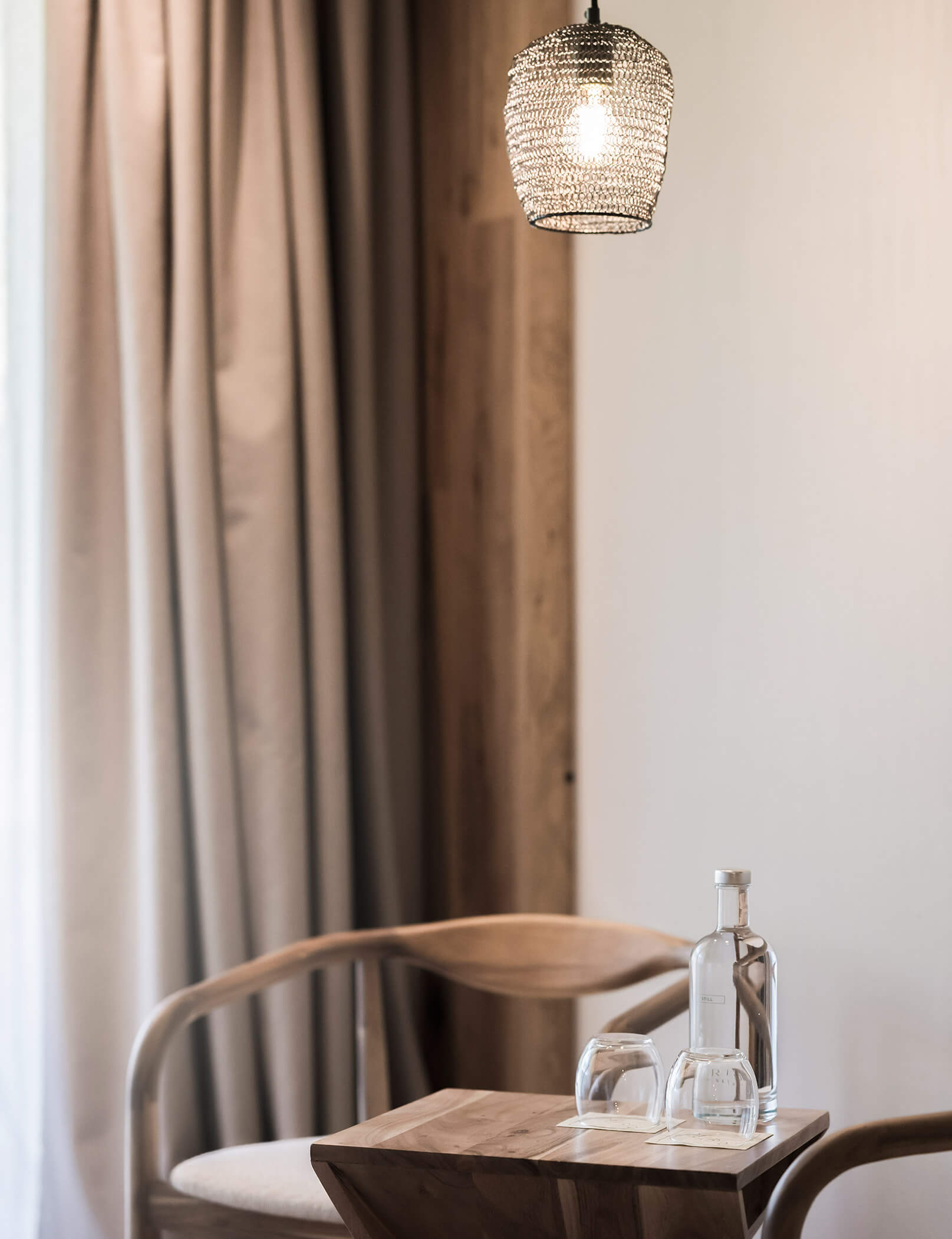 Lampada moderna e tavolo di legno sottostante con due bicchieri e una bottiglia d'acqua - Hotel Patris