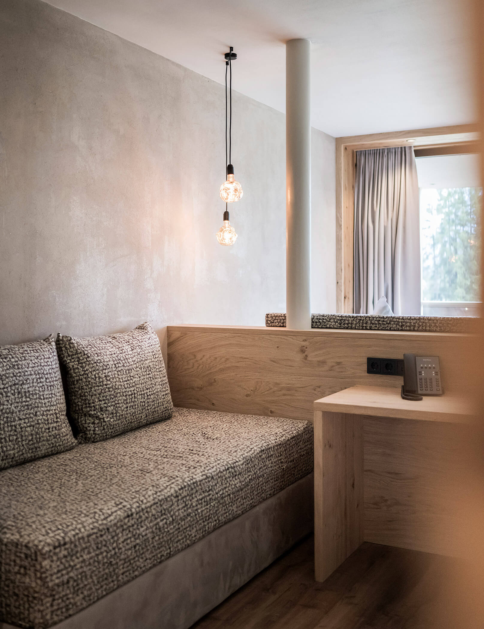 Divano con cuscini e tavolo in legno con telefono - Hotel Patris